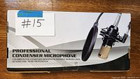 Box of a professional condenser microphone showing product image with microphone mounted on shock mount and pop filter attached.