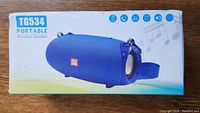 Box front showing TG534 portable wireless speaker image in blue with icons indicating Bluetooth, phone call, music, and FM radio functions.