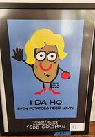 Photo of framed art poster featuring a cartoon potato character with blonde hair, red lips, and red shoes, holding a red purse, titled "I DA HO: Even Potatoes Need Lovin'" by Todd Goldman from the Stupid Factory exhibition.
