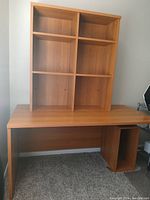 Wood desk with attached shelving unit, showing medium wood finish and four shelf compartments above the work surface.