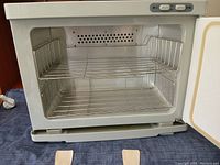 Front view of open towel warmer showing interior with two wire racks and switches on top panel.