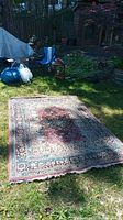 Full view of the Abrash woven Izmir rug placed outdoors on grass showing the overall condition, coloration, and size.