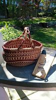 Photo of woven African Bolga basket with handle, natural fibers and traditional patterns, placed outdoors on a table