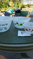 Three Federal Glass mixing bowls of varying sizes and patterns placed outdoors on a table.