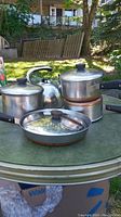 Full view of all pots and kettle on outdoor table showing condition and included items.