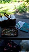 Photo showing the four items on a surface with garden background: lucite tortoiseshell box handbag with clear handles, tapestry clutch, Asian silk wallet, and Korean wallet.