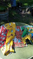 Four different fabrics themed on The Wizard of Oz laid out on a table outside, showing various colors and prints including flying monkeys and main characters.