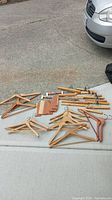 Various wooden hangers including flat, contoured, with clips, Baribocraft and cedar wood types laid out on pavement for display.