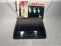 Akai AP-A301 turntable with four Beatles vinyl records behind it showing album covers
