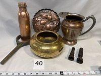 Full lot displayed: copper water bottle, koi brass display plate, copper boat oar holder, hammered copper flower pot, pair of brass hose spray nozzles, water jug.