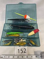 Photo of the plastic tackle box with all contents visible: fishing lures, bobbers, and weights organized inside compartments.