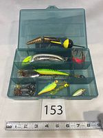 Overview of plastic tackle box showing assortment of lures in different compartments including bobber lure and deep diving Rapala CC Shad