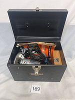 Metal black Craftsman Case opened showing router, manuals, and wooden bit box inside.