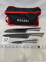 Wasabi sharpening kit including black soft carrying case with red trim, three knives and ruler for size reference
