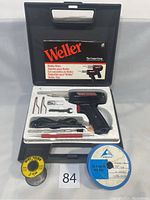 Weller soldering iron kit in original black carrying case with tray containing soldering iron, tips, tools, and solder spools, lot number label visible.