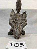 Front view of heavy metal wolf door knocker with detailed sculpted wolf face and upright tail as knocker ring.