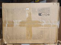 Sealed cardboard box containing the Mercer41 metal shelving unit. Box shows some tape and minor edge wear, indicating new but shipped packaging.