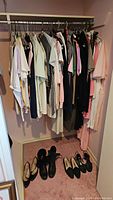 Wide view of vintage ladies clothing hanging on rack, mostly blouses, dresses, and gowns in neutral and pastel colors, sizes 10-16
