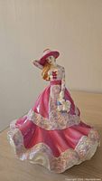 Full view of the Royal Doulton figurine showing flowing pink dress and flower purse