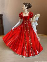 Front view of Royal Doulton Eleanor figurine showing red dress with gold floral accents, fan and shawl.