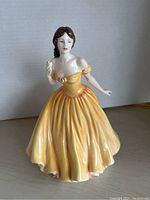 Front view of Royal Doulton Elizabeth figurine in yellow gown holding a rose