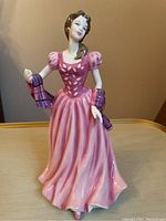 Front view of the Royal Doulton Rose Of The Glen figurine in pink dress holding a purple checkered shawl.