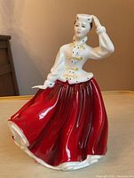 Front view of Royal Doulton Gail figurine showing detailed facial features, white jacket with gold buttons, and flowing red skirt.