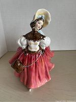 Front view showing full outfit, facial features, and the handbag carried by the figure.