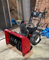 Front-left angle showing red auger housing, helical auger blades, black chute and engine.