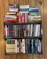 Books arranged on wooden shelves showing a mix of softcover and hardcover novels by Sue Grafton and Danielle Steel plus other reference books.