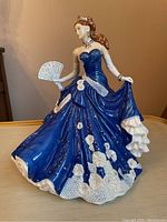 Front and side views of the porcelain figurine showing the detailed blue gown, fan, and hairstyle