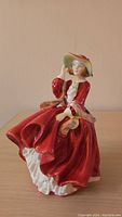 Front view of Royal Doulton porcelain figurine 'Top O the Hill' HN1834 dressed in red with a wide-brimmed hat