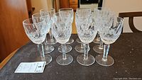 Twelve Waterford white wine glasses arranged in rows on table