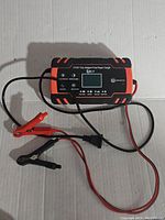 Top view of EBLY intelligent automatic car battery charger showing clamps and connection cables on a plain white background.