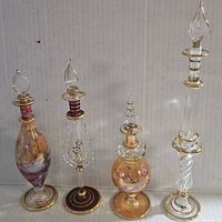 Photo showing all 4 vintage Egyptian glass perfume bottles arranged side by side against a cardboard background.