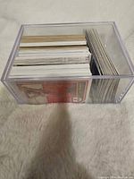 Clear plastic container filled with a large quantity of basketball and baseball cards, viewed from above showing edges and backs of cards