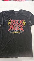 Black T-shirt front with colorful Rock Ages 10th Anniversary Tour graphic