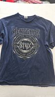 Front of large navy blue Styx Renegade concert t-shirt showing detailed front graphic with band name and dates.