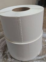 Two rolls of white 4x6 direct thermal labels stacked vertically in plastic packaging on a surface.