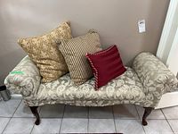 Full view of upholstered bench with three decorative pillows against wall