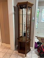 Full view of wooden display cabinet showing glass front and sides, three glass shelves, wooden top and base.