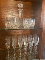 Photo showing crystal decanter with stopper on a shelf with five tumblers in front.