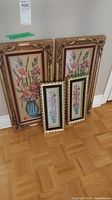 Four framed embroidered floral artworks in various sizes leaning against a wall, showing overall lot content and frames.