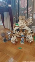 Multiple child and bear figurines on floor including two bears on rocking horse, smaller bears, and children figurines.