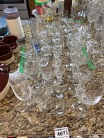 Multiple clear drinking glasses including wine, martini, and liqueur glasses on kitchen countertop with other kitchen items around
