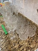 Rows of cut crystal tall wine glasses and short tumblers arranged on granite counter