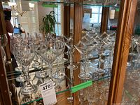 Photo showing 10 wine glasses with crystal cut patterns on the left side and 9 smooth martini glasses on the right side arranged inside a cabinet.