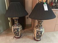 Pair of ceramic table lamps with black fabric shades shown side by side on carpet.