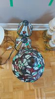 Three lamps shown from top view: two matching lamps with geometric stained glass shades and one with floral pattern.