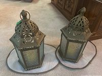 Pair of brown metal and frosted textured glass hexagonal lanterns on round beige mats on carpet